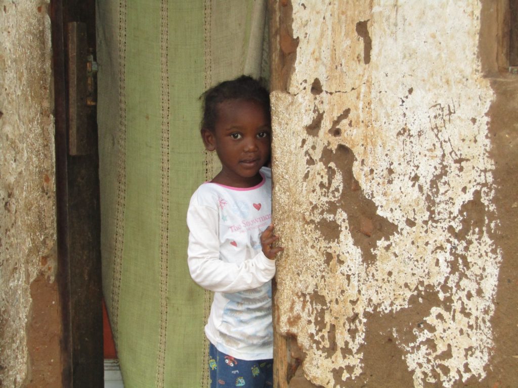 A small girl peaking from behind a pillar